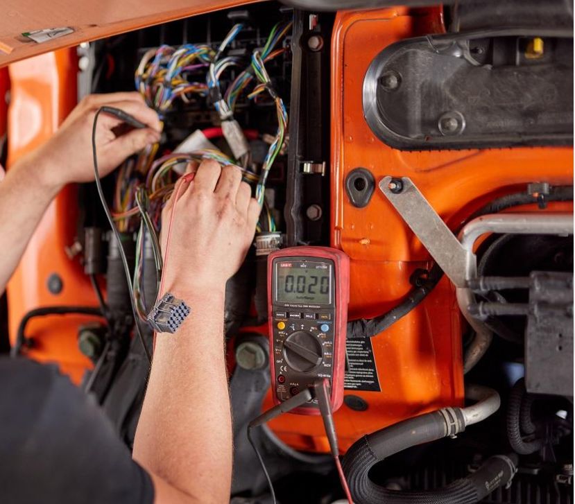 Technician measuring Caterpillar excavator sensor power supply voltage with a digital multimeter during CID 0269 FMI 03 troubleshooting
